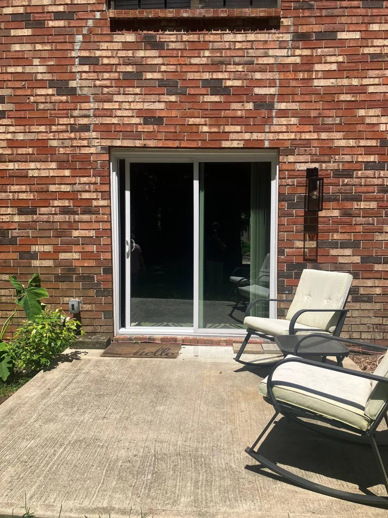 Bare concrete patio behind a brick house