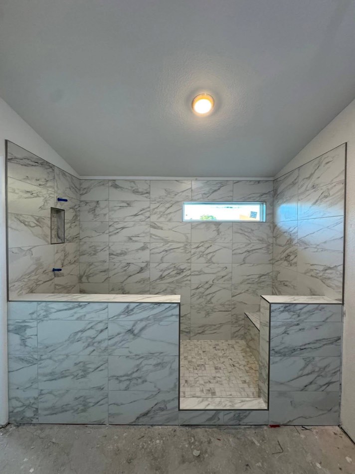 Marble walls with mosaic floor and built-in tile bench mid-install
