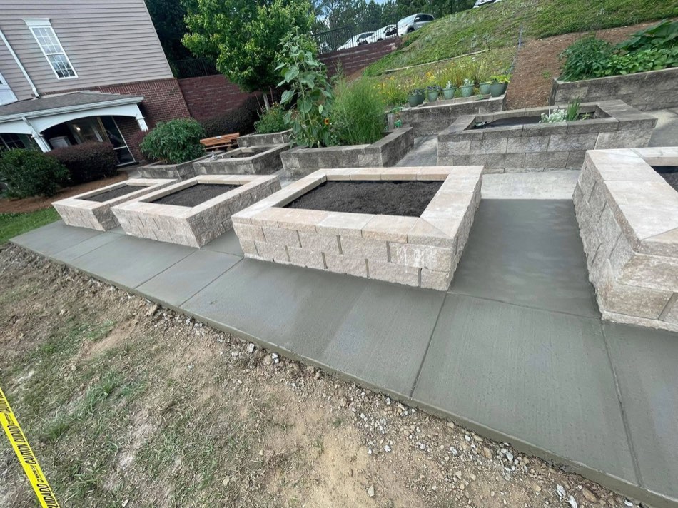 Tiered broom-finish walkway with stone planters on hillside