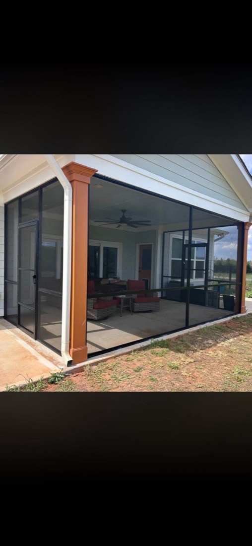 Finished screen porch with orange columns and wicker furniture