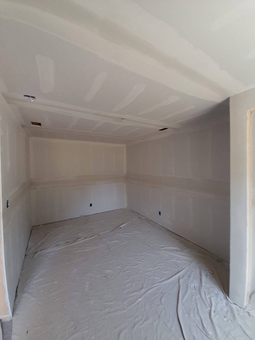 Wide mudded room with tape bands across walls and ceiling