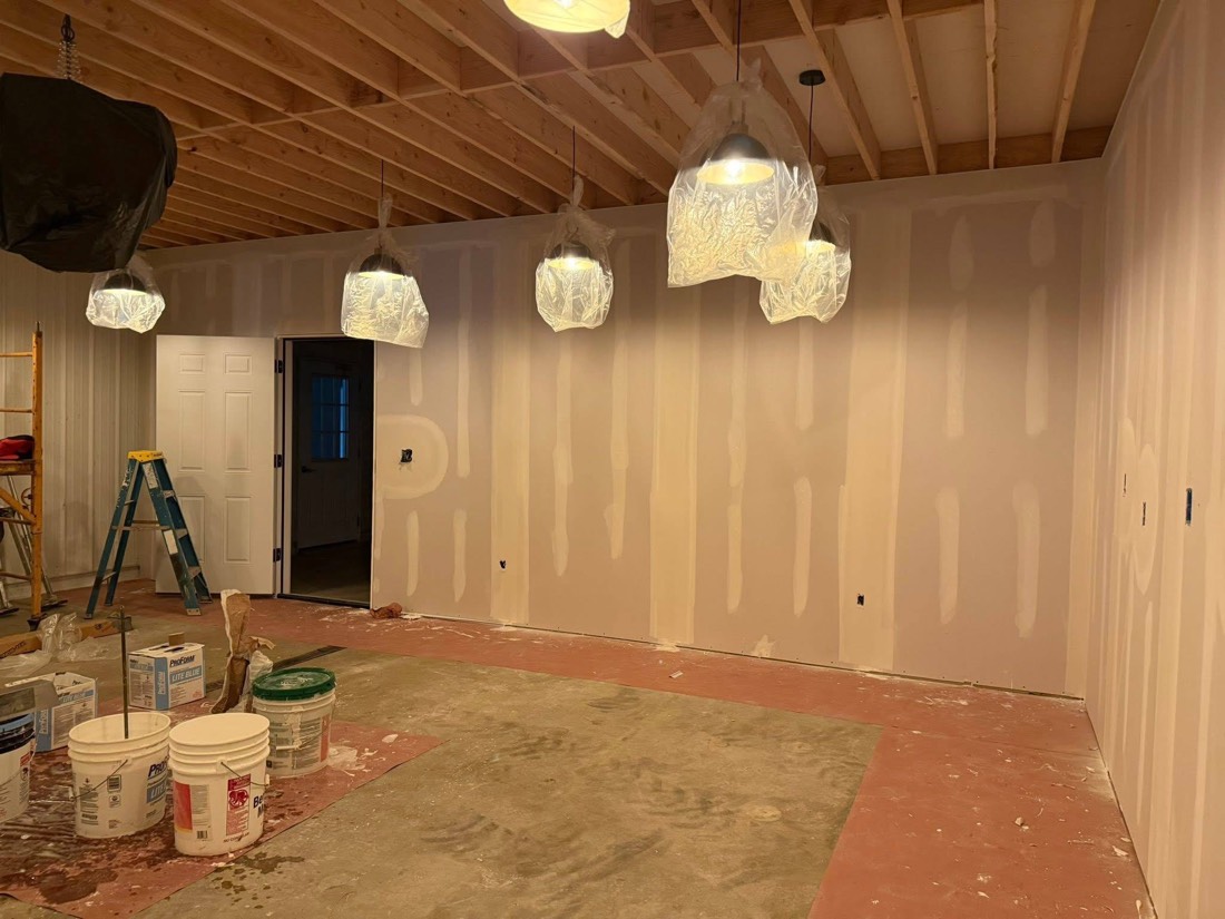 Freshly mudded wall with pendant lights wrapped in plastic