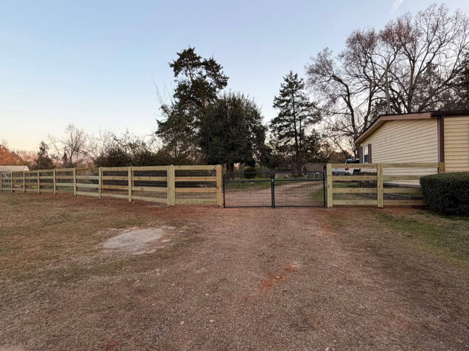 4-board ranch fence with metal drive gate at dusk