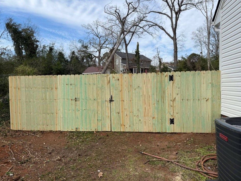 Double-gate wood privacy fence fresh build with hardware visible