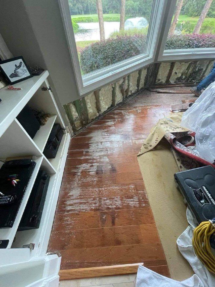Water-damage demo with wet floor and exposed wall