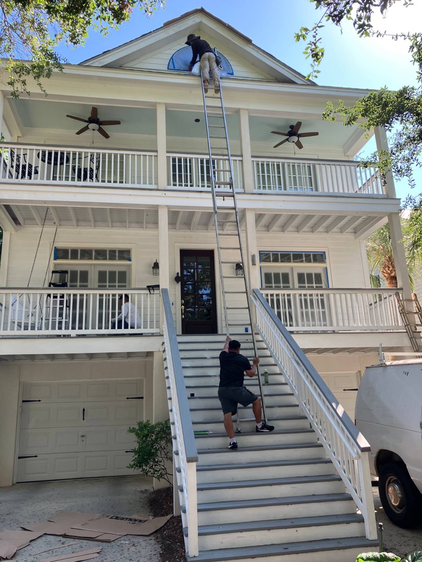 Two-story Lowcountry home with painters on a tall ladder