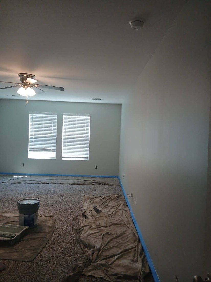 Bedroom in progress with drop cloth and paint bucket