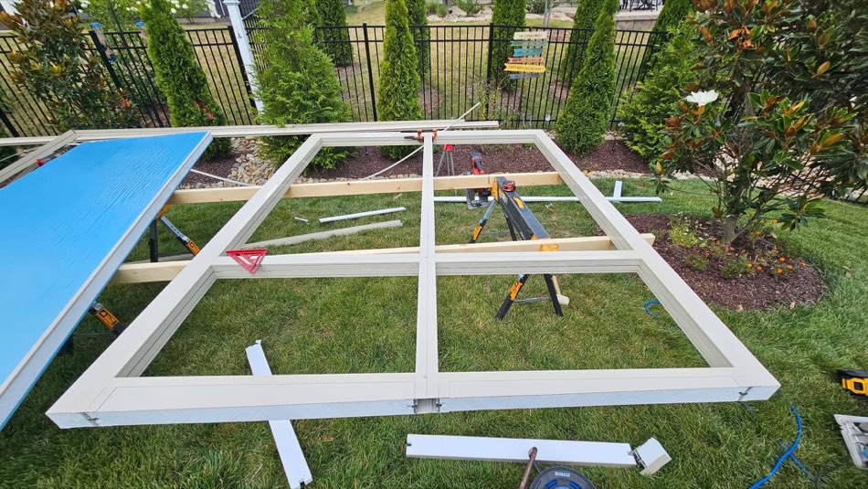 Sunroom framing laid out on grass with fresh lumber and sawhorses