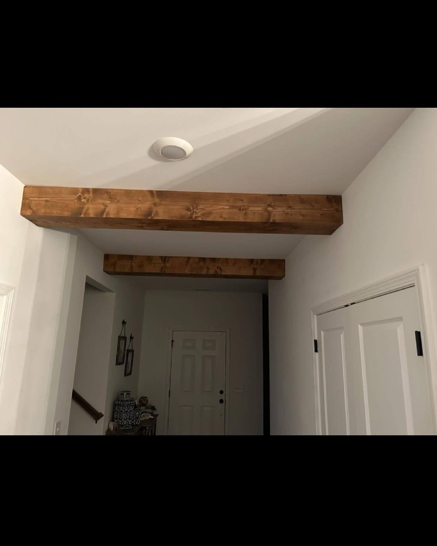 Wood box beams installed across a finished foyer ceiling