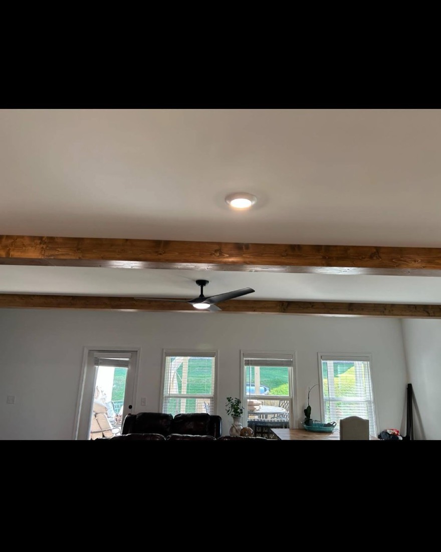 Wood beams across a great room ceiling with windows
